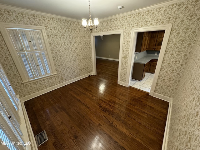 unfurnished dining area with a notable chandelier, ornamental molding, and hardwood / wood-style floors