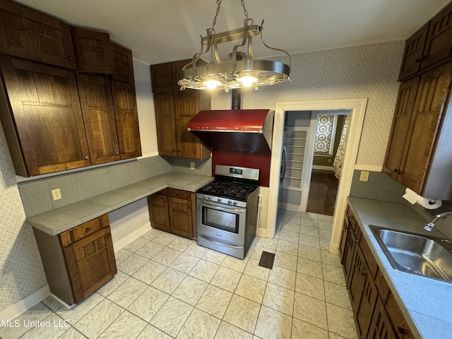 kitchen with sink, range hood, gas range, light tile patterned floors, and a chandelier