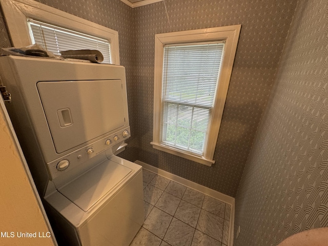 washroom with stacked washer and dryer and light tile patterned floors