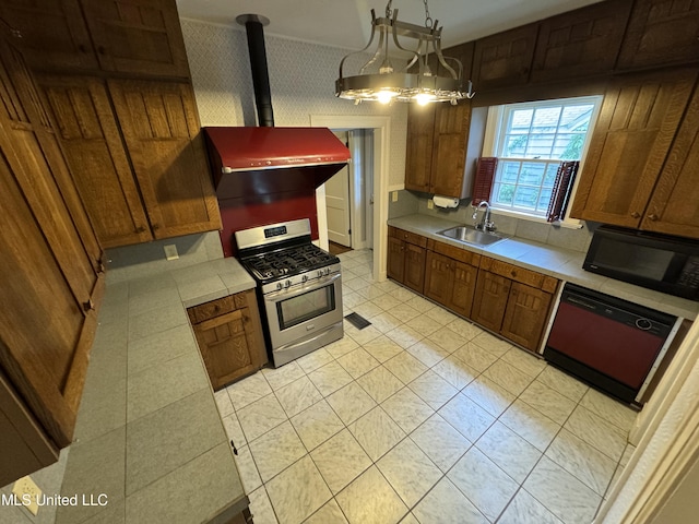 kitchen featuring a notable chandelier, black appliances, pendant lighting, a wood stove, and sink