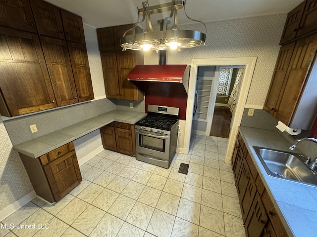 kitchen featuring gas range, a notable chandelier, sink, and light tile patterned floors