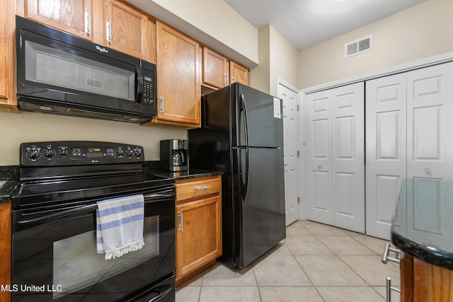 kitchen with black appliances, light tile patterned flooring, and dark stone counters