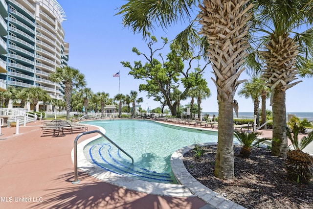 view of pool with a patio and a water view