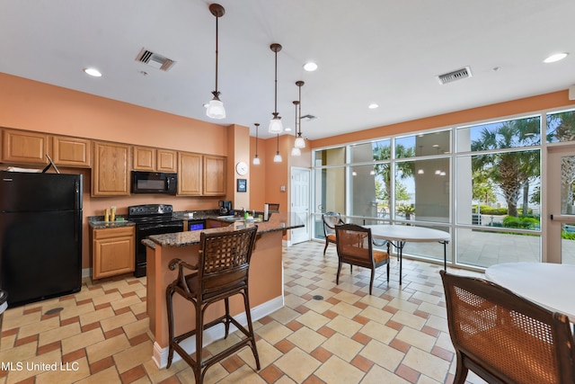 kitchen with dark stone countertops, kitchen peninsula, decorative light fixtures, a breakfast bar area, and black appliances