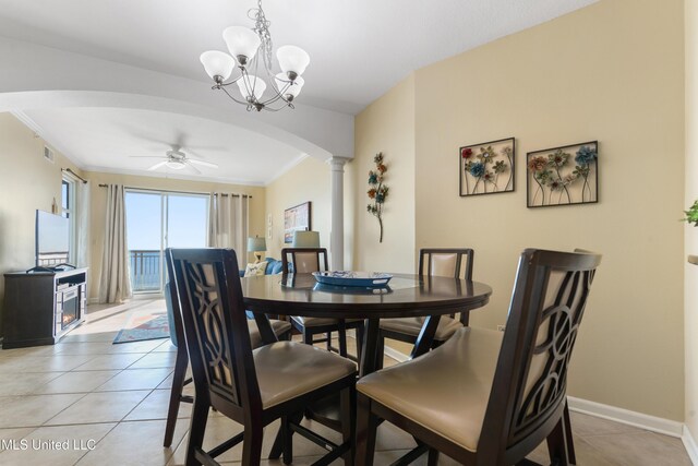 tiled dining space with decorative columns, ceiling fan with notable chandelier, and ornamental molding