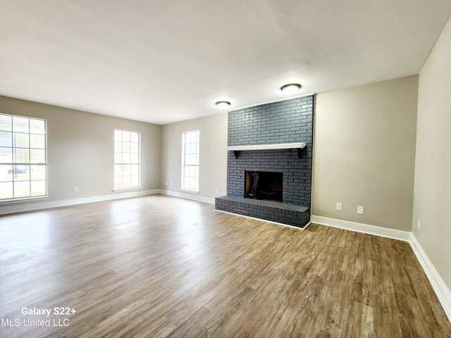 unfurnished living room with a brick fireplace and hardwood / wood-style floors