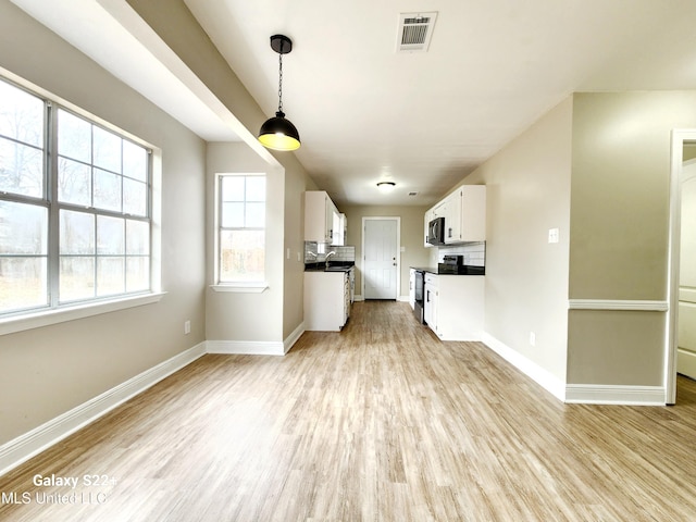 kitchen featuring light hardwood / wood-style flooring, stainless steel electric stove, hanging light fixtures, and white cabinets