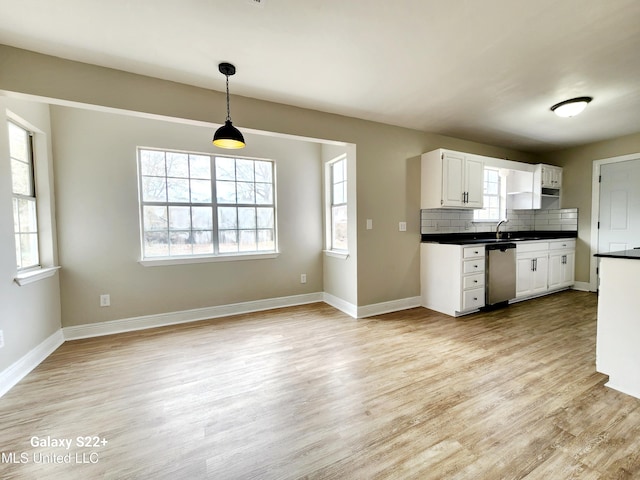 kitchen featuring decorative light fixtures, light wood-type flooring, stainless steel dishwasher, white cabinets, and backsplash