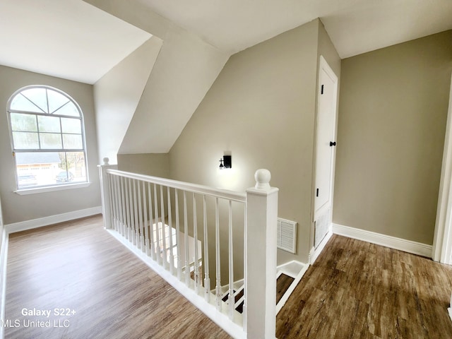 hall featuring hardwood / wood-style flooring and vaulted ceiling