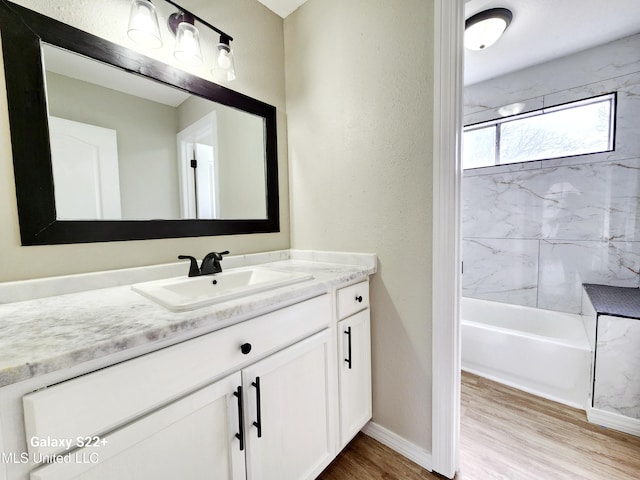 bathroom featuring wood-type flooring, vanity, and tiled shower / bath