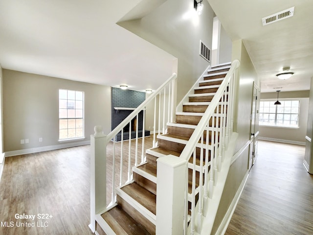 staircase with plenty of natural light and hardwood / wood-style floors