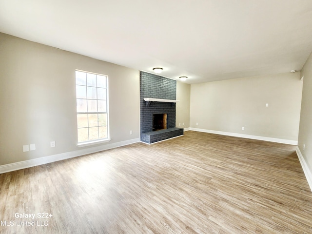 unfurnished living room featuring a brick fireplace and light wood-type flooring