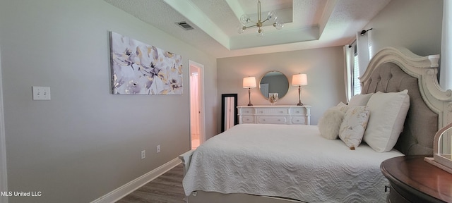 8422 Kaleki Way, Diamondhead, MS 39525 - bedroom featuring dark wood-style floors, baseboards, a tray ceiling, and a chandelier
