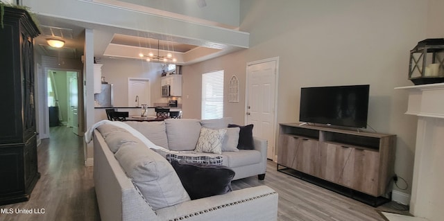 8422 Kaleki Way, Diamondhead, MS 39525 - living area with light wood-type flooring, a chandelier, a tray ceiling, and baseboards