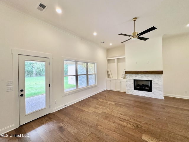 unfurnished living room with a healthy amount of sunlight, wood-type flooring, a fireplace, and ceiling fan