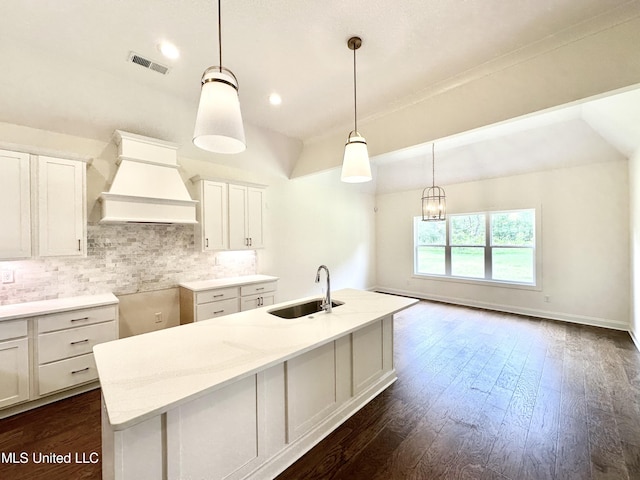 kitchen featuring backsplash, dark hardwood / wood-style floors, custom range hood, decorative light fixtures, and sink