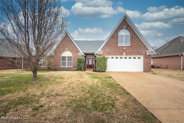 traditional home with a shingled roof, a front yard, brick siding, and driveway