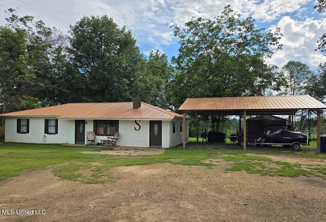 view of front of property with a carport, dirt driveway, metal roof, and a front yard