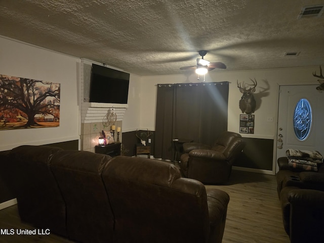 living room with a ceiling fan, a textured ceiling, wood finished floors, and baseboards