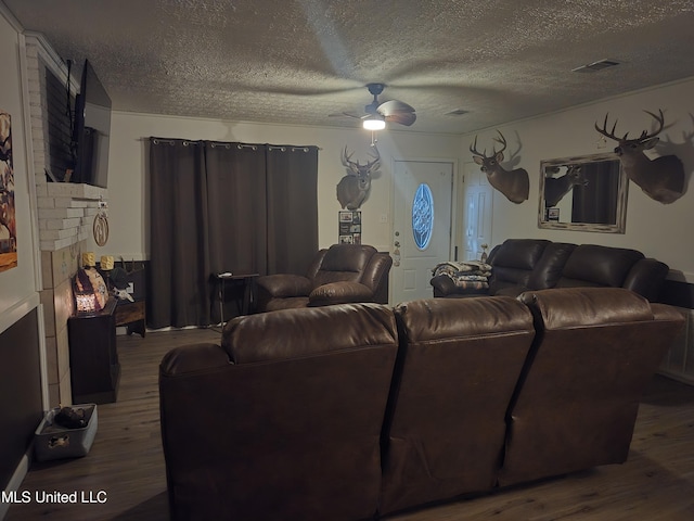 living area featuring wood finished floors, a textured ceiling, ceiling fan, and a fireplace