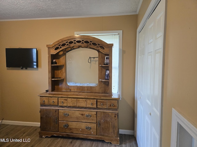 detailed view of wood finished floors, a textured ceiling, baseboards, and crown molding