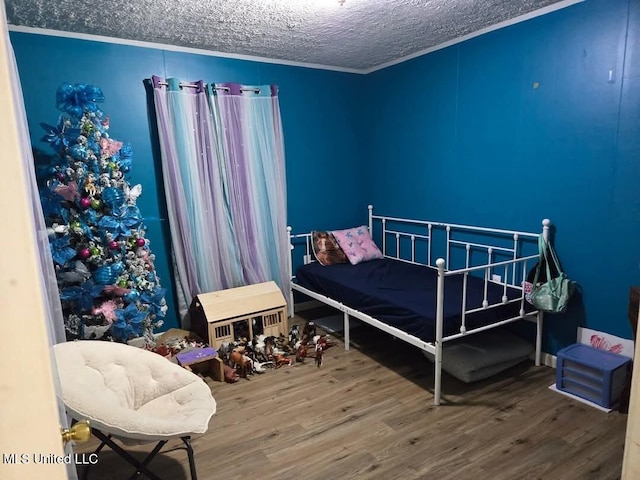 bedroom featuring wood finished floors, a textured ceiling, and ornamental molding