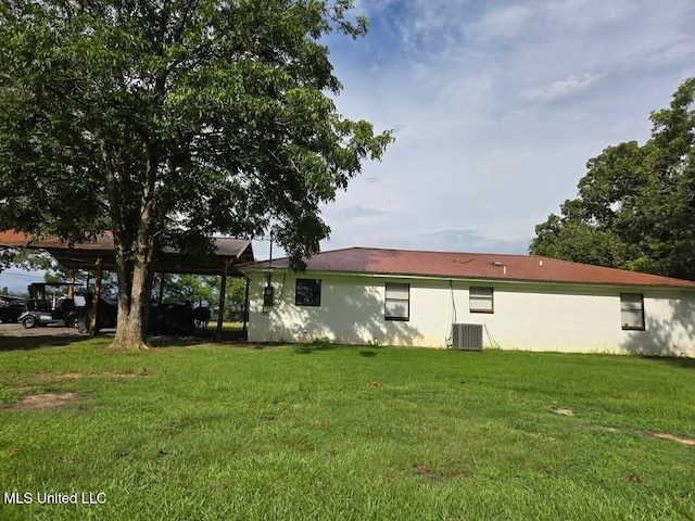 rear view of property with central AC unit and a lawn