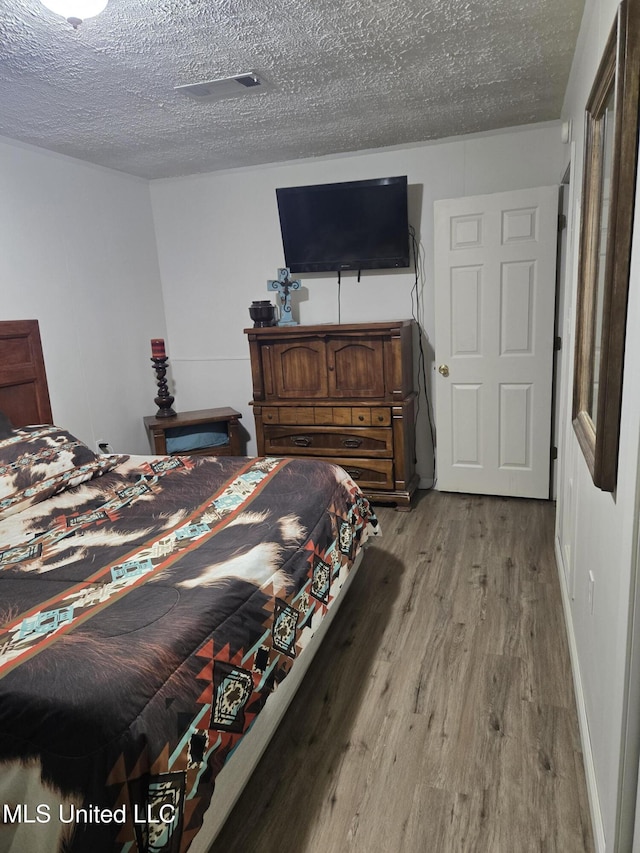 bedroom with light wood-style floors and a textured ceiling