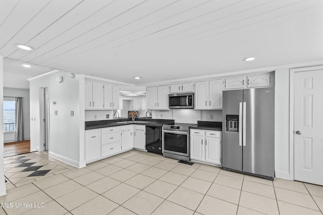 kitchen with light tile patterned floors, stainless steel appliances, dark countertops, white cabinetry, and baseboards