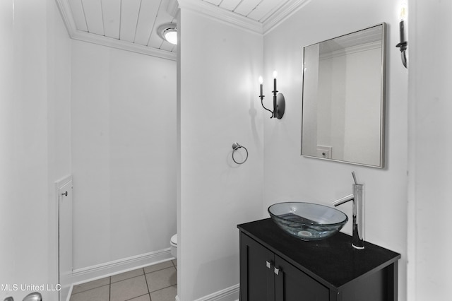 bathroom with toilet, vanity, baseboards, tile patterned floors, and crown molding