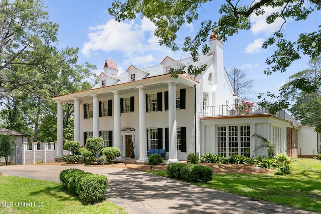 greek revival house featuring a front yard and a balcony