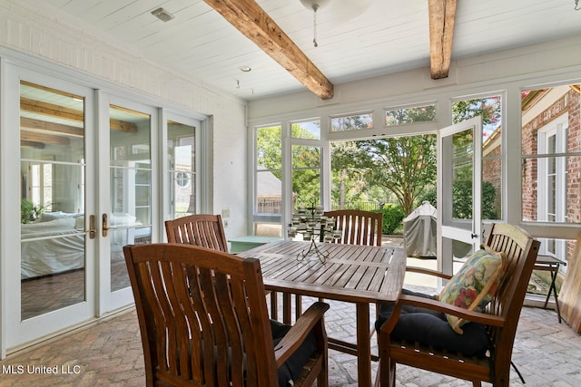 sunroom / solarium featuring beam ceiling and french doors