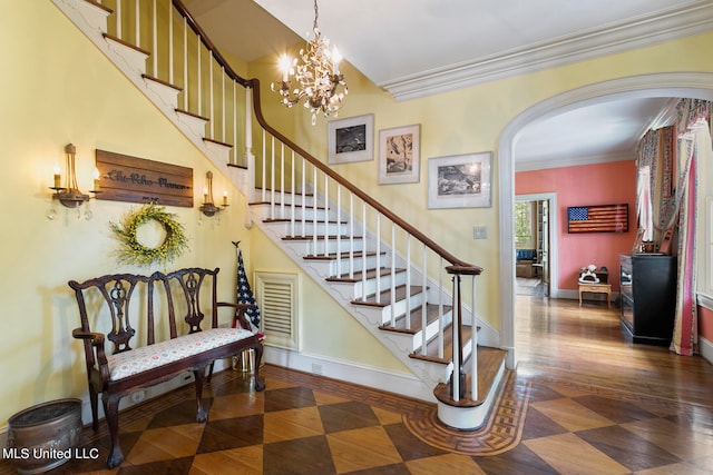 stairs with crown molding, wood-type flooring, and an inviting chandelier