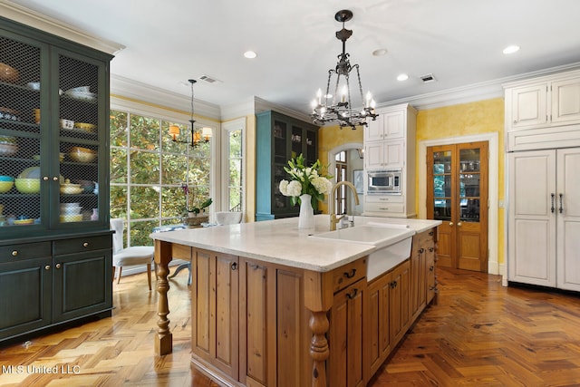 kitchen with a center island with sink, sink, light stone countertops, and hanging light fixtures