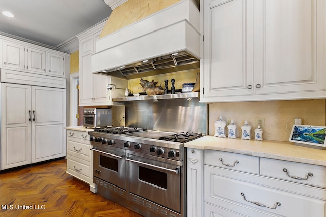 kitchen featuring custom range hood, dark parquet flooring, crown molding, double oven range, and white cabinets