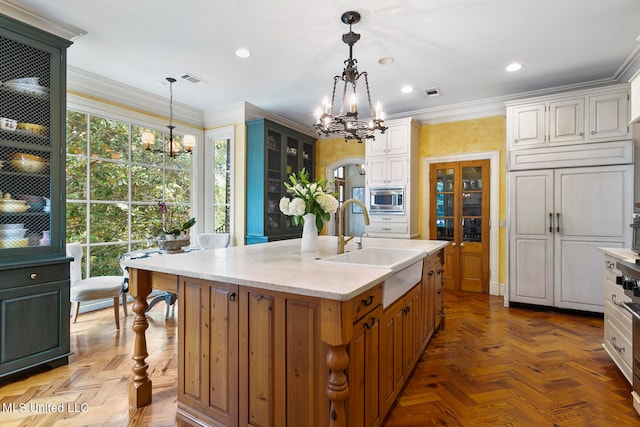 kitchen with a wealth of natural light, a kitchen island with sink, and parquet floors