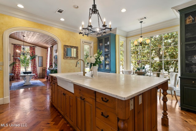 kitchen featuring sink, an island with sink, hanging light fixtures, and dark parquet flooring