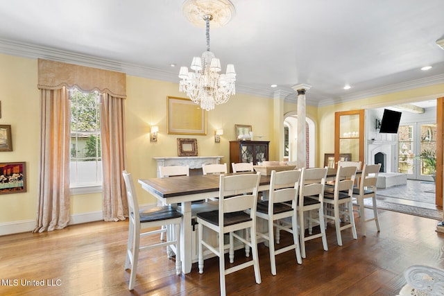 dining room with an inviting chandelier, crown molding, light hardwood / wood-style floors, and plenty of natural light