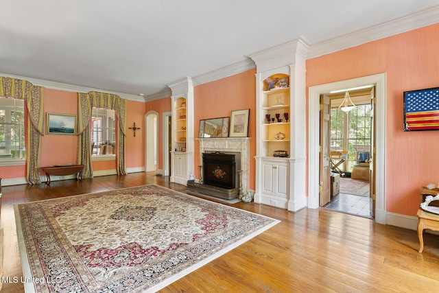 living room featuring hardwood / wood-style flooring, ornamental molding, and built in shelves