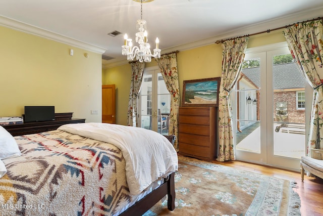 bedroom featuring a notable chandelier, access to outside, hardwood / wood-style flooring, ornamental molding, and french doors