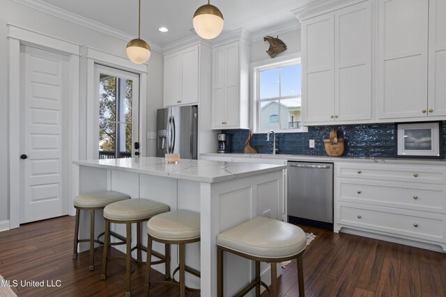 122 Aiken Rd, Waveland, MS 39576 - kitchen with a kitchen island, ornamental molding, white cabinets, appliances with stainless steel finishes, and backsplash