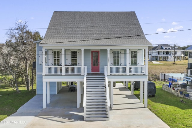122 Aiken Rd, Waveland, MS 39576 - coastal inspired home with a carport, a porch, a front lawn, and a shingled roof
