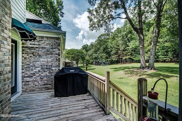 wooden terrace featuring a yard and a grill