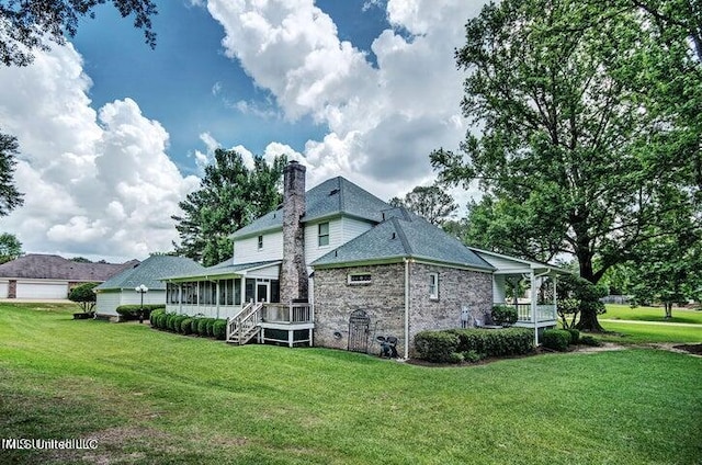 back of house featuring a sunroom, stairs, a yard, and a chimney