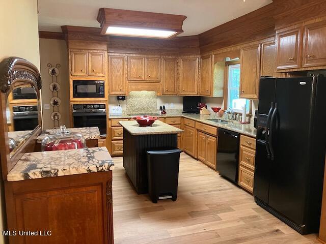 kitchen featuring black appliances, a kitchen island, light wood-style floors, and light countertops