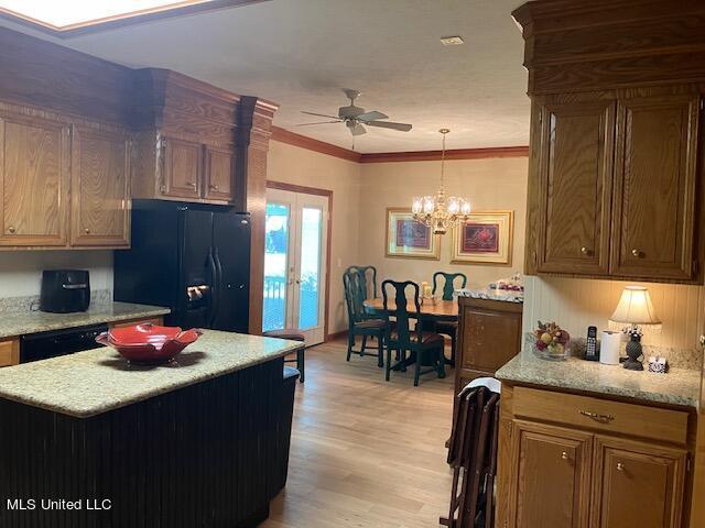 kitchen with light wood-style floors, black fridge, ornamental molding, hanging light fixtures, and ceiling fan with notable chandelier