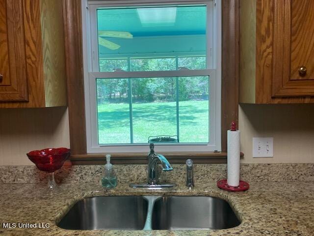 interior details with light stone countertops, brown cabinets, and a sink