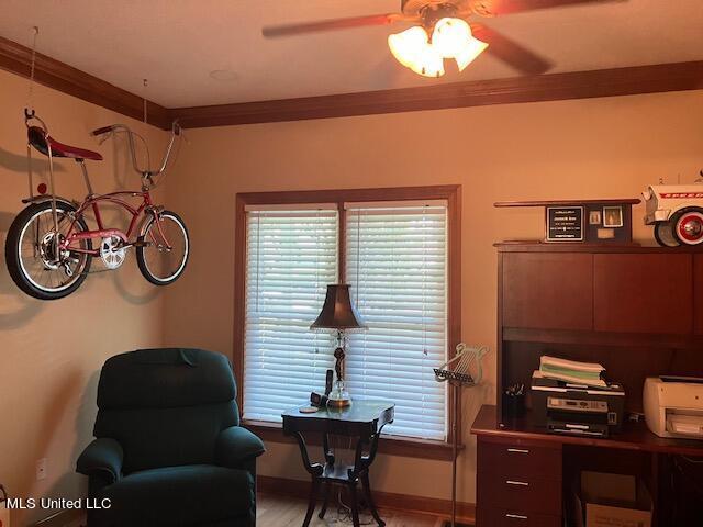 office area featuring baseboards, light wood-style flooring, ceiling fan, and crown molding