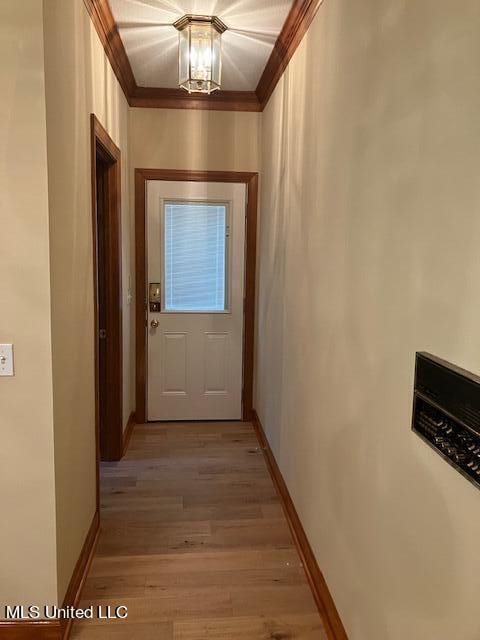 doorway to outside featuring ornamental molding, light wood finished floors, and baseboards