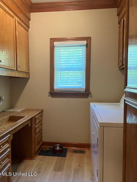 laundry room featuring light hardwood / wood-style flooring, ornamental molding, sink, cabinets, and washer and dryer